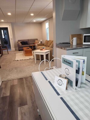 Una sala moderna con un sofá, una mesa de centro y una cocina con microondas.