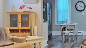 A living room with a wooden cabinet, a sofa, and a dining area with a table and chairs. - Warm northwoods beach-style apartment walking distance to OreBeGone & Mesabi Trl (Gilbert)