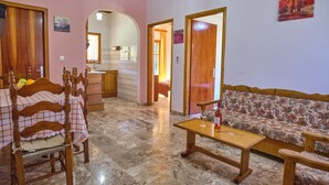 A cozy living room with a sofa, wooden chairs, a coffee table, and a tiled floor. - Theodora Apartment 2 Agios Stefanos Corfu (Corfu)
