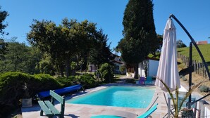 A rectangular swimming pool with a tiled deck, surrounded by a fence. There are two lounge chairs and a bench near the pool. - Chalet Avec vue Magnifique sur les Montagnes Basques, à 3 Minutes Despelette (Itxassou)
