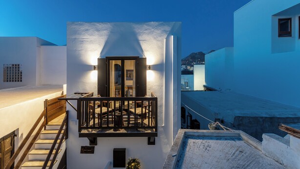 A white building with a balcony, a staircase, and a view of the city in the background. - Domus Castrum (Νάξος)