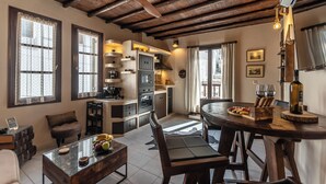 A cozy kitchen with wooden beams, a dining table, and a coffee machine. - Domus Castrum (Νάξος)