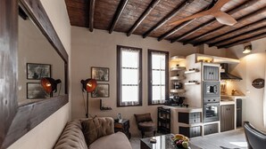 A living room with a sofa, a coffee table with fruit, and a kitchen area with cabinets and appliances. - Domus Castrum (Νάξος)