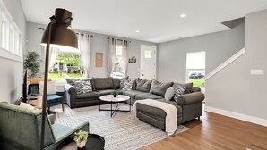 A spacious living room with a sectional sofa, a coffee table, and a floor lamp. - Modern & Spacious Downtown Master Suite Palace! (Indianapolis)