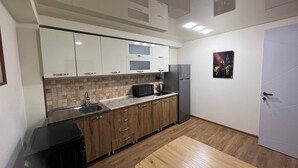 Eine moderne Küche mit weißen Schränken, einer Mikrowelle, einem Kühlschrank und einer Spüle.