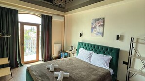 Ein Hotelzimmer mit einem großen Bett, einem Schreibtisch mit Stuhl, einem Fenster mit Vorhängen und Blick nach draußen.
