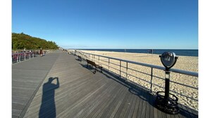 A wooden boardwalk with benches and a telescope on the right side.