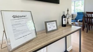 A reception desk with a welcome sign, a framed certificate, and a decorative bottle.