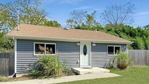 A single-story house with a front porch, a small front yard, and a wooden fence.