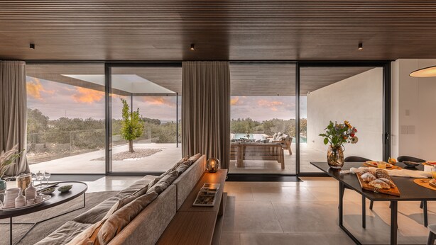 Una sala de estar moderna con sofá, mesa de comedor y vistas al exterior.