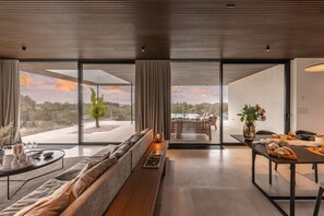 Una sala de estar moderna con sofá, mesa de comedor y vistas al exterior.