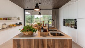 Una cocina moderna con una isla de madera, electrodomésticos integrados y un amplio ventanal con vistas al exterior.