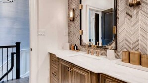 Un baño con un espejo grande, dos lavamanos y un mueble-tocador con cajones.