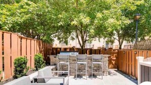 Un espacio patio con cerramiento de madera, mobiliario exterior y una pila de libros.