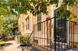 A brick building with a gated entrance, a visible number '1217', and a pathway leading to the entrance.