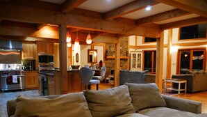 A cozy living room with a large beige sofa, wooden beams, and a stone fireplace.