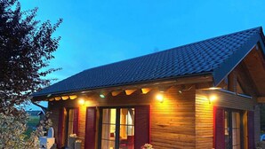 A wooden building with a sloped roof, large windows, and outdoor seating. - Vacation cottage Schorenmoos-Lodge (Dietmannsried)