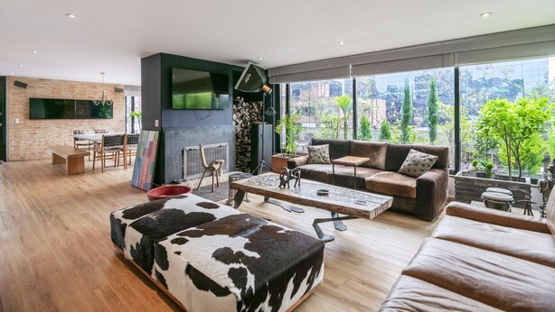 Ein geräumiges Wohnzimmer mit großem Fenster, Kamin, Sofa und Essbereich.
