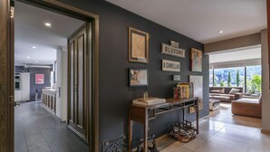 Ein modernes Wohnzimmer mit dunkler Wand, einem Holzkonsolentisch und Blick auf die Stadt durch große Fenster.
