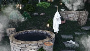 Un bain à remous en pierre, entouré de rochers et de verdure, avec une serviette et des chaussons à proximité.