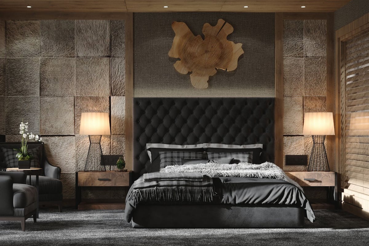 A modern bedroom with a large bed, a tufted headboard, and a stone wall with a wooden art piece.