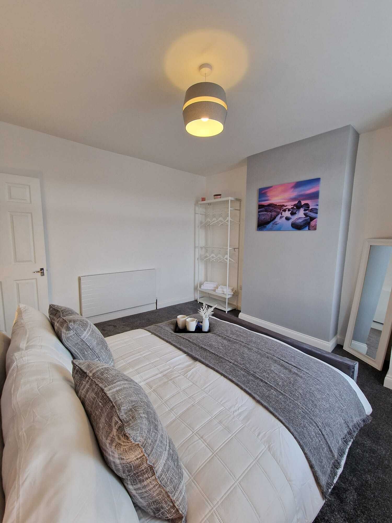 A bedroom with a bed, a bedside table, a wall-mounted shelf, and a painting.