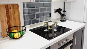 Une cuisine moderne avec une plaque de cuisson noire, des armoires blanches et un pare-feu en carreaux.