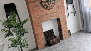 Un salon moderne avec une cheminée en briques, une grande horloge et une plante en pot.