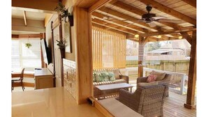 A wooden deck with wicker furniture and a view of a fenced area.