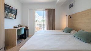 Une chambre d’hôtel équipée d’un lit, d’un bureau, d’une chaise, d’une télévision et offrant une vue sur l’extérieur.