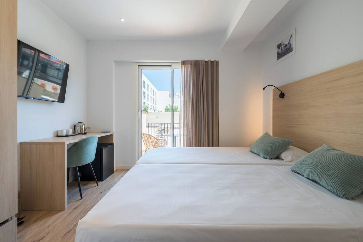 Een hotelkamer met een bed, een bureau, een stoel, een televisie en uitzicht.