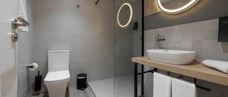 A modern bathroom with a toilet, bidet, and a glass shower enclosure.