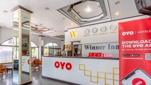 Ein Hotel-Empfangsbereich mit großem OYO-Logo, einer digitalen Uhr und einem Schild für das Winner Inn.