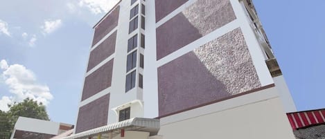 A tall hotel with a modern architectural design, featuring a prominent vertical window section and a covered entrance area.
