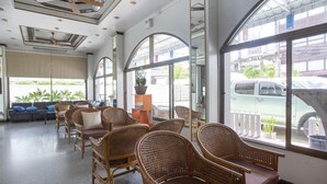 Eine geräumige Lobby mit Korbstühlen, einer Couch und einem großen Fenster mit Blick auf die Straße.