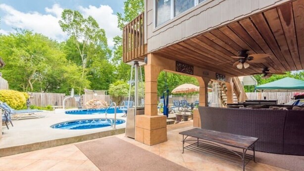 En trädgård med pool, utomhusmöbler och en täckt uteplats.