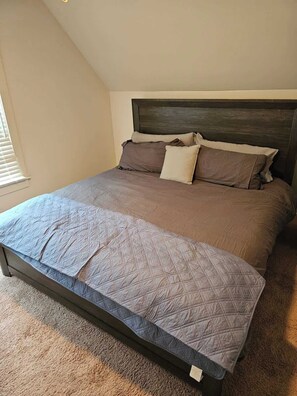 A bedroom with a bed, headboard, and a window. - Modern Midtown home with 3 king beds (Memphis)