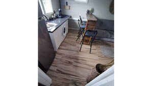 A compact kitchen with a washing machine, a sink, and a small dining area with chairs. - Les parasols de madinina - Palm tree at the bungalow (Gros-Morne)