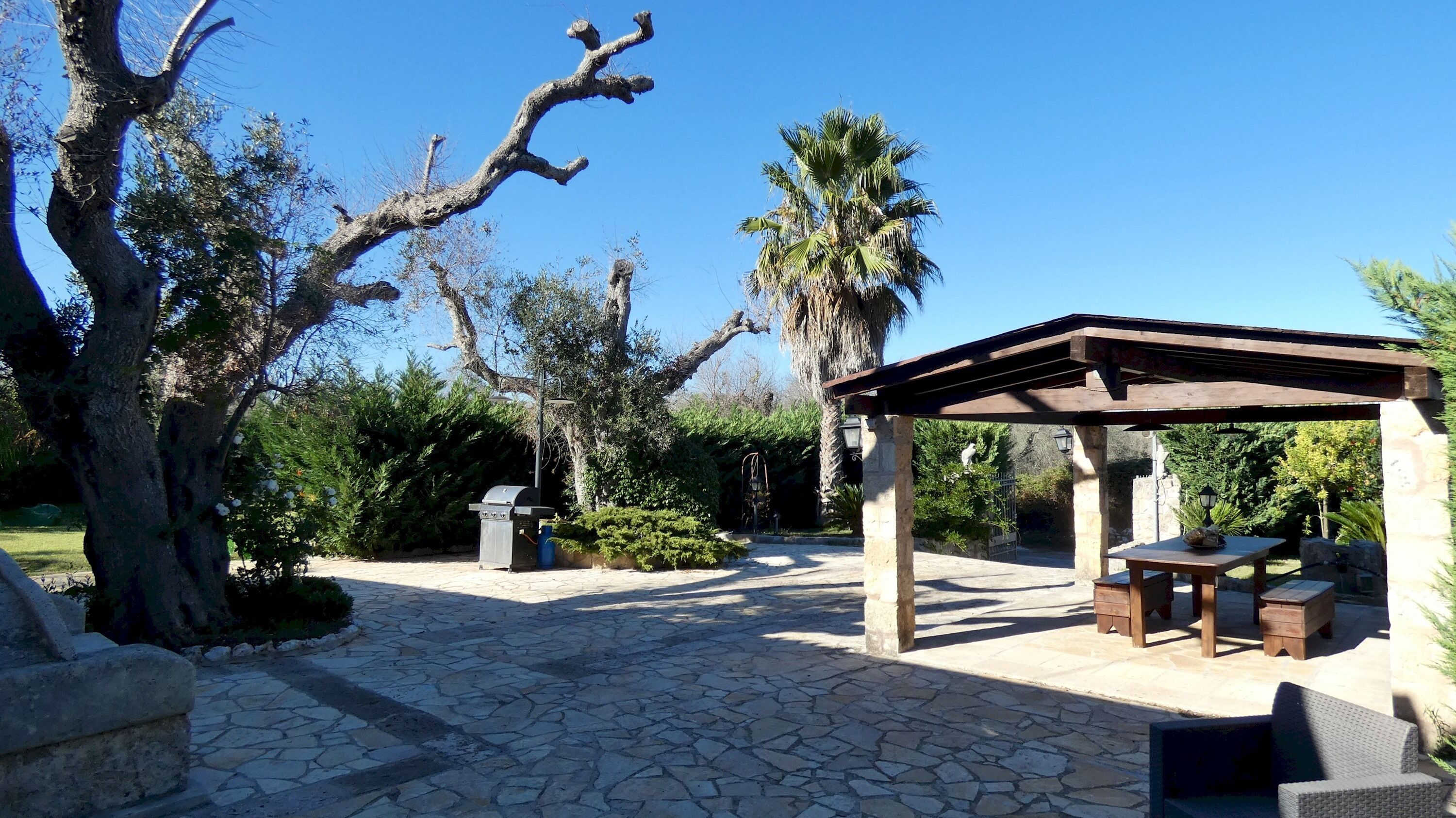 A stone-paved patio with a wooden pergola and seating area.