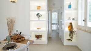 A modern interior with white walls, a dining area with a table set for two, and a hallway leading to another room. - Villa Machri - Con Piscina Privata E Ampio Giardino Vicina Al Mare (Alessano)