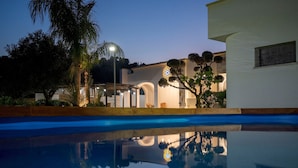 A modern house with a swimming pool, arched windows, and a well-lit exterior. - Villa Machri - Con Piscina Privata E Ampio Giardino Vicina Al Mare (Alessano)