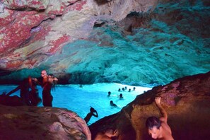 A cave with a pool where people are swimming and climbing.