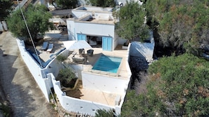 Une villa moderne dotée d’une piscine sur le toit, d’un espace salon extérieur et d’un mur de soutènement en pierre.
