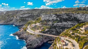 Una strada costiera con un ponte, scogliere rocciose e edifici lungo il mare.