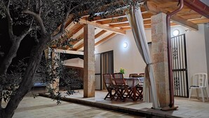 An outdoor patio area with a wooden pergola, stone pillars, and a dining table with chairs. - Casa Celeste - Immersa Nella Natura con Piscina Privata nel Salento (Corsano)