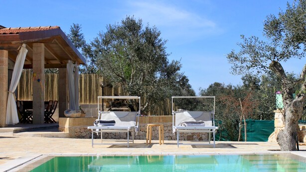 A pool area with two lounge chairs and a stone wall. - Casa Celeste - Immersa Nella Natura con Piscina Privata nel Salento (Corsano)