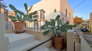 A building with a balcony, two potted cacti, and a clear sky.