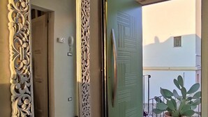 A hallway with a large ornate mirror, a green door, and a potted plant on a balcony.