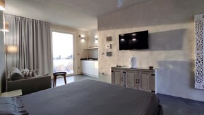 A hotel room with a bed, a desk, a chair, a TV, and a view of the city through the window.