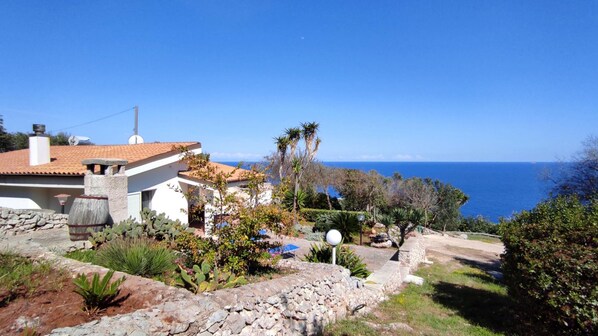 Ein Küstenanwesen mit einem weißen Gebäude, Steinmauern und Blick auf das Meer.